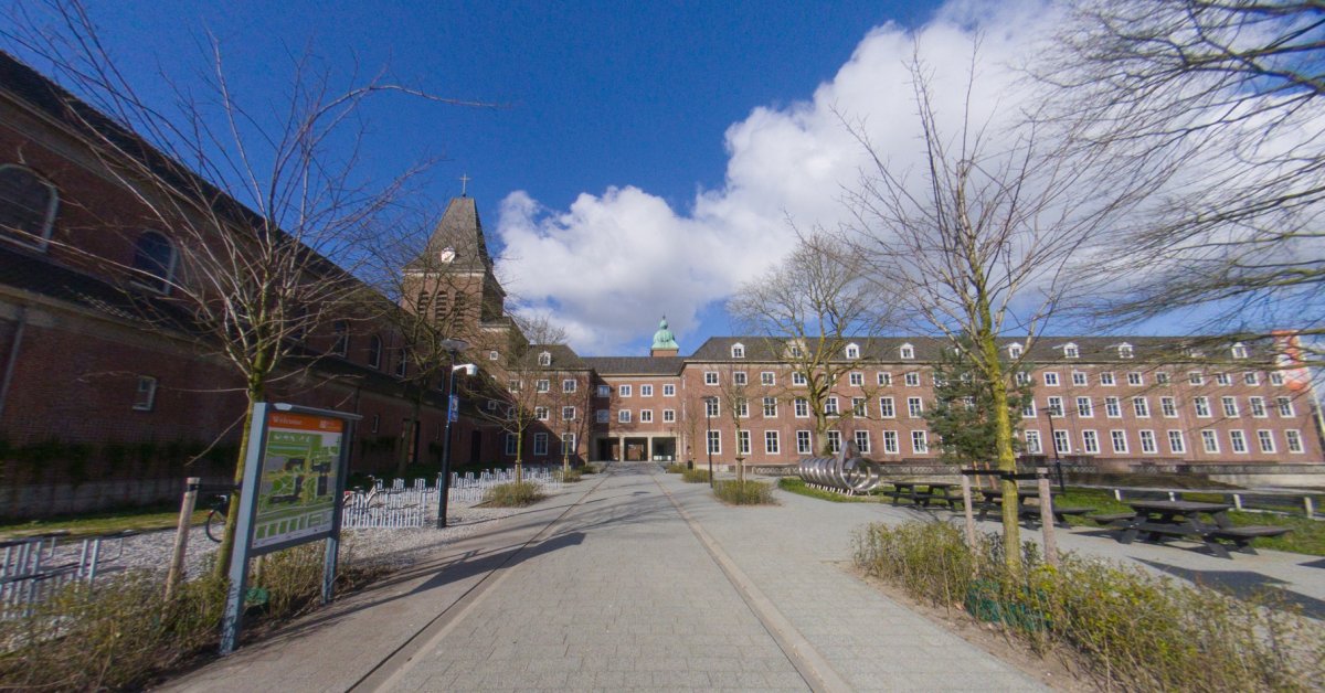 Binnenplaats van rode bakstenen gebouwen met op de achtergrond een kerktoren